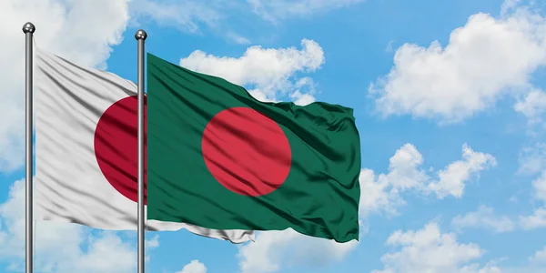 Bandera de Japón y Bangladesh ondeando en el viento contra el cielo azul nublado blanco juntos. Concepto diplomático, relaciones internacionales . — Foto de Stock