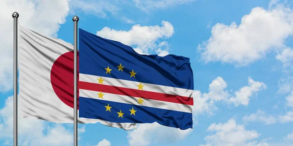 Bandera de Japón y Cabo Verde ondeando en el viento contra el cielo azul nublado blanco juntos. Concepto diplomático, relaciones internacionales . — Foto de Stock