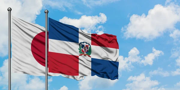日本とドミニカ共和国の旗は、一緒に白い曇り青い空に対して風に手を振る。外交概念、国際関係. — ストック写真