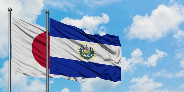 Japan- und El-Salvador-Flagge wehen gemeinsam im Wind vor dem wolkenverhangenen blauen Himmel. Diplomatie-Konzept, internationale Beziehungen. — Stockfoto