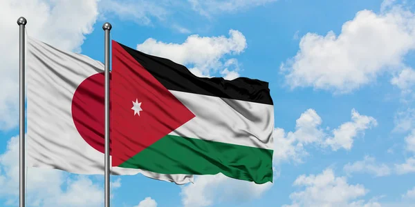 Japani ja Jordania lippu heiluttavat tuulessa valkoista pilvistä sinistä taivasta vasten yhdessä. Diplomatian käsite, kansainväliset suhteet . — kuvapankkivalokuva