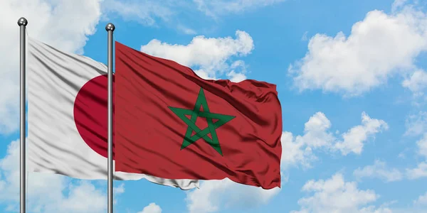 Bandera de Japón y Marruecos ondeando en el viento contra el cielo azul nublado blanco juntos. Concepto diplomático, relaciones internacionales . — Foto de Stock