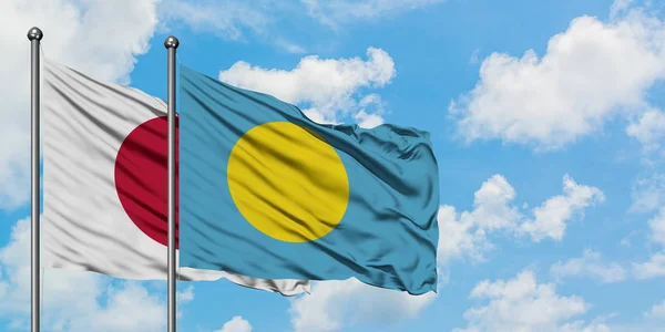 Bandera de Japón y Palau ondeando en el viento contra el cielo azul nublado blanco juntos. Concepto diplomático, relaciones internacionales . — Foto de Stock