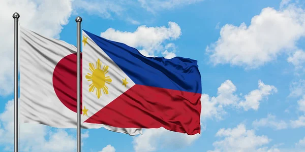 Bandeira do Japão e Filipinas agitando no vento contra o céu azul nublado branco juntos. Conceito de diplomacia, relações internacionais . — Fotografia de Stock