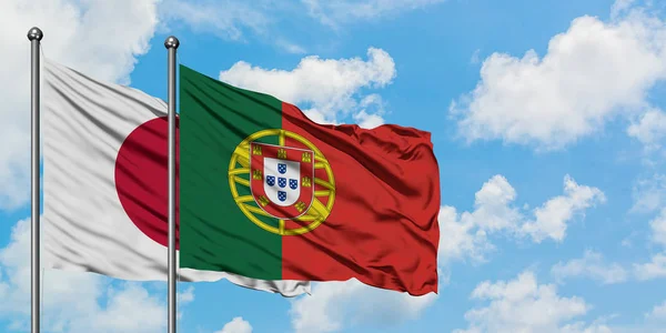 Bandera de Japón y Portugal ondeando en el viento contra el cielo azul nublado blanco juntos. Concepto diplomático, relaciones internacionales . — Foto de Stock