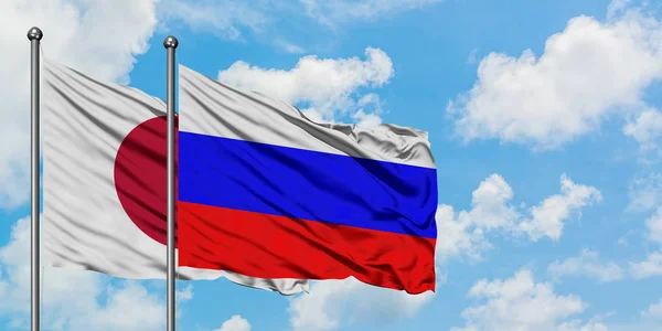 Japan and Russia flag waving in the wind against white cloudy blue sky together. Diplomacy concept, international relations. — Stock Photo, Image