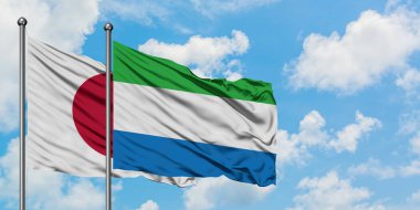 Japonya ve Sierra Leone bayrağı birlikte beyaz bulutlu mavi gökyüzüne karşı rüzgarda sallayarak. Diplomasi kavramı, uluslararası ilişkiler.