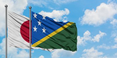 Japonya ve Solomon Adaları bayrağı birlikte beyaz bulutlu mavi gökyüzüne karşı rüzgarda sallayarak. Diplomasi kavramı, uluslararası ilişkiler.