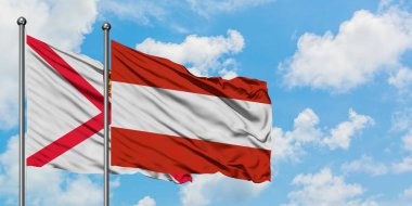 Jersey ve Avusturya bayrağı birlikte beyaz bulutlu mavi gökyüzüne karşı rüzgarda sallayarak. Diplomasi kavramı, uluslararası ilişkiler.