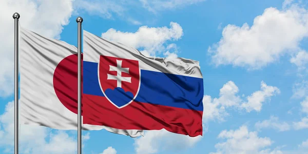 Bandera de Japón y Eslovaquia ondeando en el viento contra el cielo azul nublado blanco juntos. Concepto diplomático, relaciones internacionales . — Foto de Stock