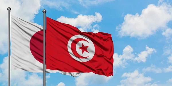 Japán és Tunézia zászló integetett a szél ellen, fehér felhős kék ég együtt. Diplomáciai koncepció, nemzetközi kapcsolatok. — Stock Fotó
