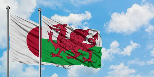 A bandeira do Japão e do País de Gales agitando no vento contra o céu azul nublado branco juntos. Conceito de diplomacia, relações internacionais . — Fotografia de Stock