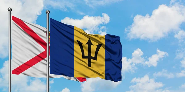 Bandera de Jersey y Barbados ondeando en el viento contra el cielo azul nublado blanco juntos. Concepto diplomático, relaciones internacionales . — Foto de Stock