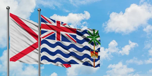Jersey och brittiska Indiska oceanen territorium flagga vifta i vinden mot vit grumlig blå himmel tillsammans. Diplomatisk koncept, internationella relationer. — Stockfoto