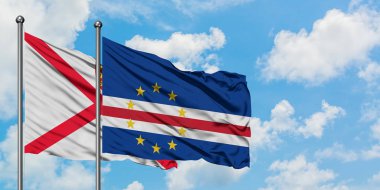 Jersey ve Cape Verde bayrağı birlikte beyaz bulutlu mavi gökyüzüne karşı rüzgarda sallayarak. Diplomasi kavramı, uluslararası ilişkiler.