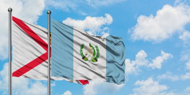 Jersey ve Guatemala bayrağı birlikte beyaz bulutlu mavi gökyüzüne karşı rüzgarda sallayarak. Diplomasi kavramı, uluslararası ilişkiler.