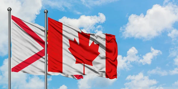 Bandera de Jersey y Canadá ondeando en el viento contra el cielo azul nublado blanco juntos. Concepto diplomático, relaciones internacionales . — Foto de Stock