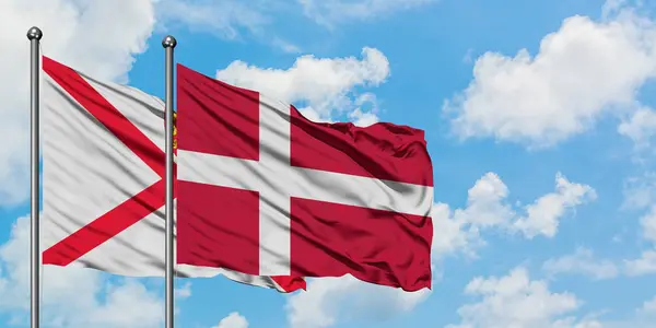 Jersey a Dánská vlajka mávali ve větru proti bíle zatažené modré obloze. Diplomacie, mezinárodní vztahy. — Stock fotografie