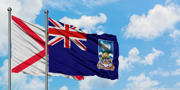 Jersey och Falklandsöarnas flagga vifta i vinden mot vit grumlig blå himmel tillsammans. Diplomatisk koncept, internationella relationer. — Stockfoto