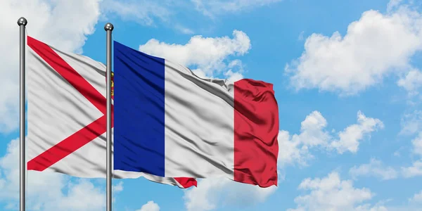 Jersey i Francji flagi machając w wiatr przed białym zachmurzone błękitne niebo razem. Koncepcja dyplomacji, stosunki międzynarodowe. — Zdjęcie stockowe