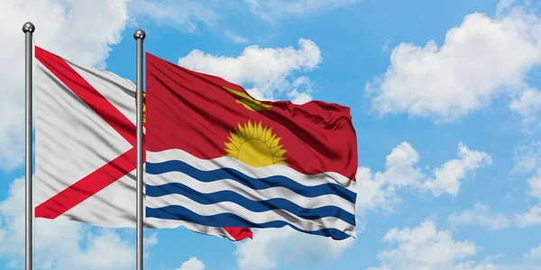 Bandera de Jersey y Kiribati ondeando en el viento contra el cielo azul nublado blanco juntos. Concepto diplomático, relaciones internacionales . — Foto de Stock