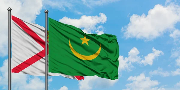 Bandera de Jersey y Mauritania ondeando en el viento contra el cielo azul nublado blanco juntos. Concepto diplomático, relaciones internacionales . — Foto de Stock