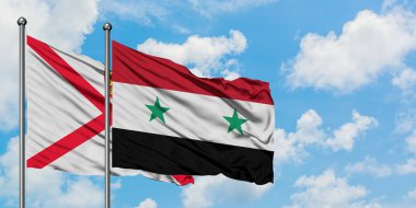 Jersey ve Suriye bayrağı birlikte beyaz bulutlu mavi gökyüzüne karşı rüzgarda sallayarak. Diplomasi kavramı, uluslararası ilişkiler.