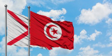Jersey ve Tunus bayrağı birlikte beyaz bulutlu mavi gökyüzüne karşı rüzgarda sallayarak. Diplomasi kavramı, uluslararası ilişkiler.