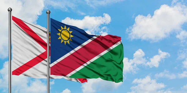 Jerseyská a Namibijská vlajka mával ve větru proti bílé zatažené modré obloze dohromady. Diplomacie, mezinárodní vztahy. — Stock fotografie