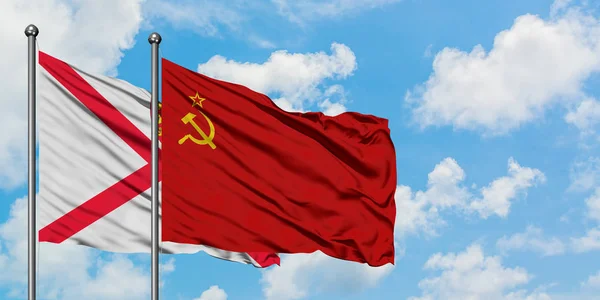 Jersey y la bandera de la Unión Soviética ondeando en el viento contra el cielo azul nublado blanco juntos. Concepto diplomático, relaciones internacionales . — Foto de Stock