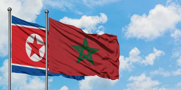 Bandera de Corea del Norte y Marruecos ondeando en el viento contra el cielo azul nublado blanco juntos. Concepto diplomático, relaciones internacionales . — Foto de Stock