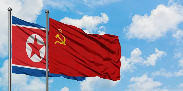 Észak-Korea és a Szovjetunió zászló integetett a szél ellen, fehér felhős kék ég együtt. Diplomáciai koncepció, nemzetközi kapcsolatok. — Stock Fotó