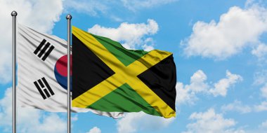 Güney Kore ve Jamaika bayrağı birlikte beyaz bulutlu mavi gökyüzüne karşı rüzgarda sallayarak. Diplomasi kavramı, uluslararası ilişkiler.