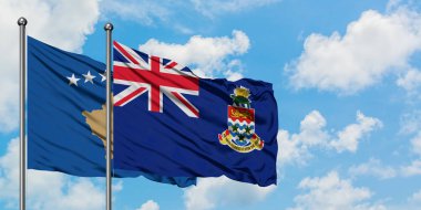 Kosova ve Cayman Adaları bayrağı birlikte beyaz bulutlu mavi gökyüzüne karşı rüzgarda sallayarak. Diplomasi kavramı, uluslararası ilişkiler.