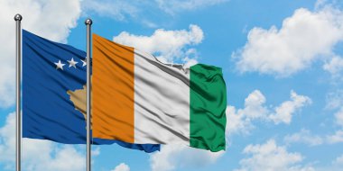 Kosova ve Fildişi Sahili bayrağı birlikte beyaz bulutlu mavi gökyüzüne karşı rüzgarda sallayarak. Diplomasi kavramı, uluslararası ilişkiler.