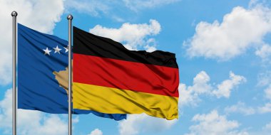 Kosovo and Germany flag waving in the wind against white cloudy blue sky together. Diplomacy concept, international relations. clipart