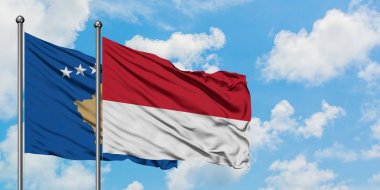 Kosova ve Monako bayrağı birlikte beyaz bulutlu mavi gökyüzüne karşı rüzgarda sallayarak. Diplomasi kavramı, uluslararası ilişkiler.