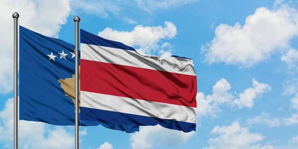 Bandera de Kosovo y Costa Rica ondeando en el viento contra el cielo azul nublado blanco juntos. Concepto diplomático, relaciones internacionales . — Foto de Stock