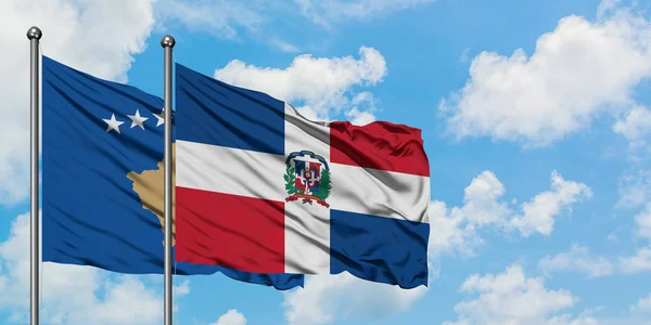 Kosovo- und Dominikanische Republik-Flagge wehen gemeinsam im Wind vor weißem wolkenlosem blauen Himmel. Diplomatie-Konzept, internationale Beziehungen. — Stockfoto