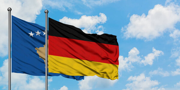 Kosovo and Germany flag waving in the wind against white cloudy blue sky together. Diplomacy concept, international relations.