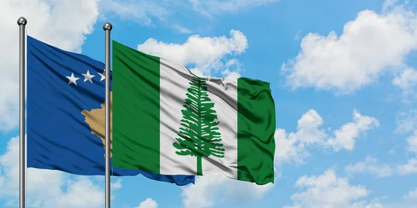 Bandera de Kosovo y Norfolk Island ondeando en el viento contra el cielo azul nublado blanco juntos. Concepto diplomático, relaciones internacionales . — Foto de Stock