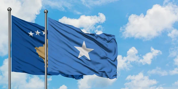 Bandera de Kosovo y Somalia ondeando en el viento contra el cielo azul nublado blanco juntos. Concepto diplomático, relaciones internacionales . — Foto de Stock