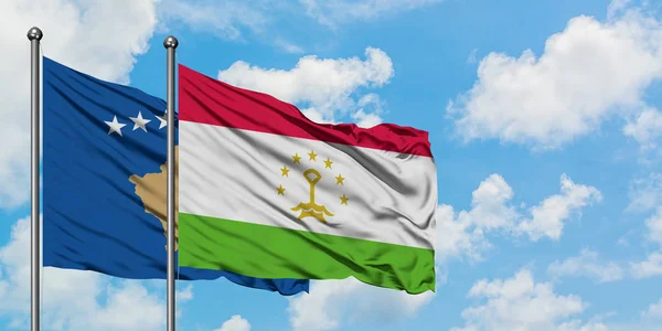 Bandera de Kosovo y Tayikistán ondeando en el viento contra el cielo azul nublado blanco juntos. Concepto diplomático, relaciones internacionales . — Foto de Stock