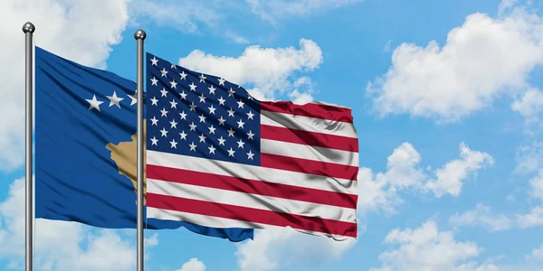 A bandeira do Kosovo e dos Estados Unidos agitando no vento contra o céu azul nublado branco juntos. Conceito de diplomacia, relações internacionais . — Fotografia de Stock