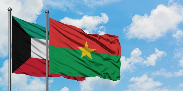 Bandera de Kuwait y Burkina Faso ondeando en el viento contra el cielo azul nublado blanco juntos. Concepto diplomático, relaciones internacionales . — Foto de Stock