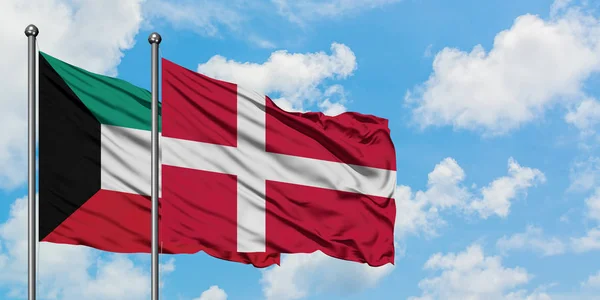 Kuwait och Danmark flagga vifta i vinden mot vit grumlig blå himmel tillsammans. Diplomatisk koncept, internationella relationer. — Stockfoto