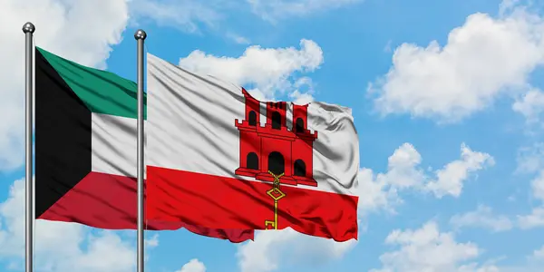 Bandera de Kuwait y Gibraltar ondeando en el viento contra el cielo azul nublado blanco juntos. Concepto diplomático, relaciones internacionales . — Foto de Stock