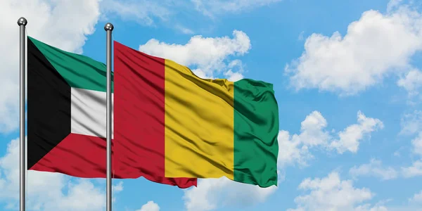 Bandera de Kuwait y Guinea ondeando en el viento contra el cielo azul nublado blanco juntos. Concepto diplomático, relaciones internacionales . — Foto de Stock