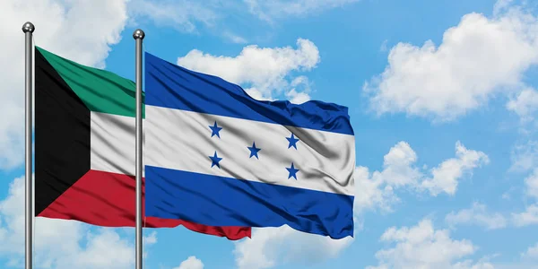 Bandera de Kuwait y Honduras ondeando en el viento contra el cielo azul nublado blanco juntos. Concepto diplomático, relaciones internacionales . — Foto de Stock