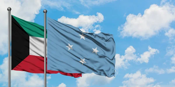 Bandera de Kuwait y Micronesia ondeando en el viento contra el cielo azul nublado blanco juntos. Concepto diplomático, relaciones internacionales . — Foto de Stock